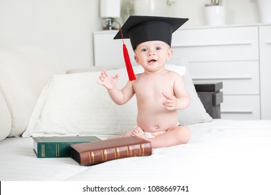 Smiling baby in black graduation hat looking in camera