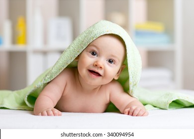 Smiling baby boy after shower or bath with towel on head 
