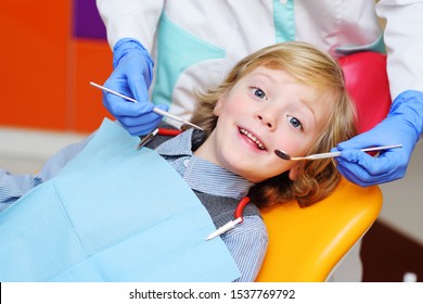 smiling baby boy with blond curly hair in dental chair. Pediatric dentistry.