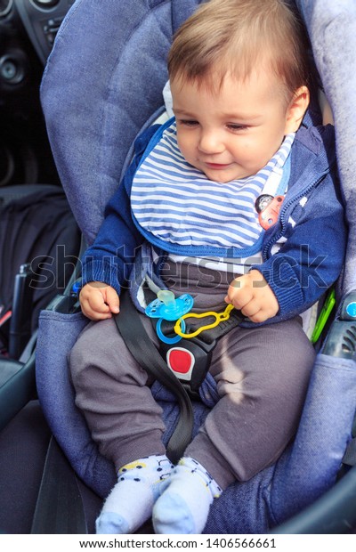 Smiling baby boy child sitting in car seat\
with safety belt locked\
protection\
