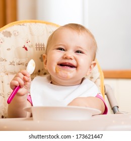 Smiling Baby Eating Food On Kitchen