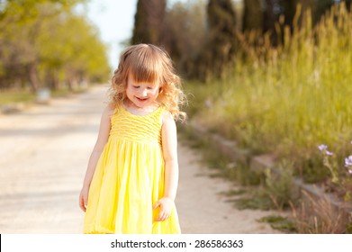 Smiling Baby Girl 3-4 Year Old Walking In Park Outdoors. Looking Down. Childhood. Playful.