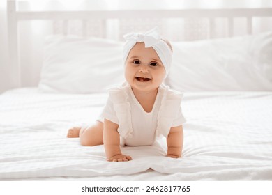 smiling baby girl laughing crawling on a bed in white clothes in a bright room, a place for text, happy healthy baby close-up, children's laughter. - Powered by Shutterstock