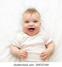 Smiling Baby Lying On A White Bed. Good Morning!