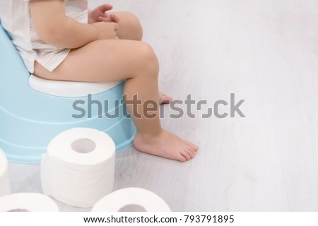 smiling baby sitting on chamber pot with toilet paper rolls