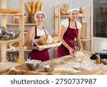 Smiling bakers at work and baking baguettes, buns and delicious bread. Women bakers prepare raw dough, knead it and make French baguettes.