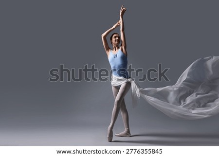 Smiling ballerina practicing dance moves with white veil on grey background. Space for text