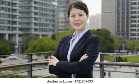 Smiling Bank Manager Welcoming Warm Personality Bright Big Smile Outside Office Building. Confident Business Woman Crossed Arms Face Camera Happy Looks Outdoor On Balcony Terrace Relaxing Break Time