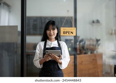 Smiling barista in apron holding a coffee cup with a welcoming open sign in the background at a cozy café.

 - Powered by Shutterstock