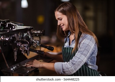 Smiling barista cleaning coffee machine in the bar - Powered by Shutterstock