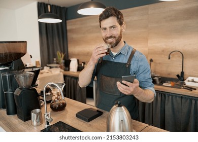 Smiling Barista Drinking Coffee And Scrolling Through Social Media Feed During Lunch At Workplace