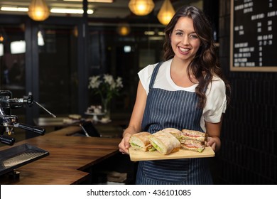 Smiling Barista Holding Plate With Sandwich At Coffee Shop