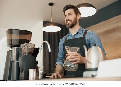 Smiling Barista Holds In His Hands Empty Glass Vessel For Making Filter Coffee In Coffeeshop