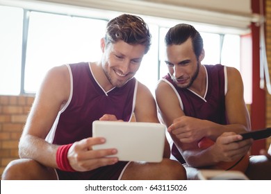 Smiling basketball players talking while using digital tablet in the court - Powered by Shutterstock