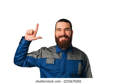 Smiling bearded male engineer wearing blue uniform points up to copy space over white background. - Powered by Shutterstock