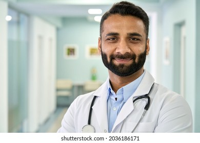 Smiling bearded male Indian doctor wearing medical coat looking at camera. Headshot portrait of ethnic hispanic man medic professional, hospital physician, confident practitioner or surgeon at work.