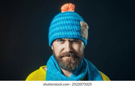 Smiling bearded man in autumn-winter style. Handsome man in warm clothes. Knitwear accessories. Fashionable guy in blue knitted hat, scarf and yellow sweater. Winter fashion for men. Winter knitwear - Powered by Shutterstock