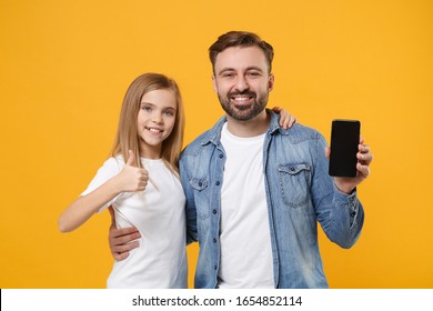 Smiling Bearded Man With Child Baby Girl. Father Little Kid Daughter Isolated On Yellow Background. Love Family Day Parenthood Childhood Concept. Hold Mobile Phone With Empty Screen Showing Thumb Up