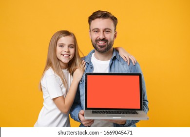 Smiling Bearded Man With Child Baby Girl. Father Little Kid Daughter Isolated On Yellow Background. Love Family Day Parenthood Childhood Concept. Hold Laptop Computer With Blank Empty Screen Hugging