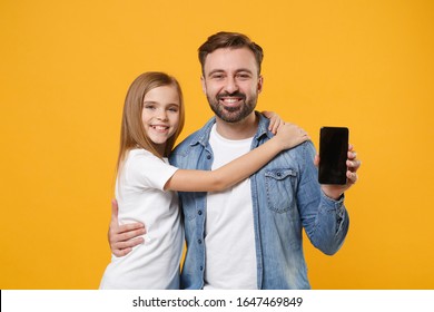 Smiling Bearded Man Have Fun With Child Baby Girl. Father Little Kid Daughter Isolated On Yellow Background. Love Family Day Parenthood Childhood Concept. Hold Mobile Phone With Empty Screen Hugging