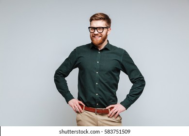 Smiling Bearded man in shirt and eyeglasses which posing with arms at hip