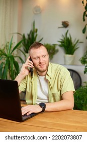 Smiling Bearded Man Talking Speaking On Phone Using Laptop. Male Employee Have Smartphone Call Cellphone With Client Or Business Partner.