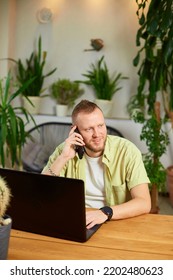 Smiling Bearded Man Talking Speaking On Phone Using Laptop. Male Employee Have Smartphone Call Cellphone With Client Or Business Partner.