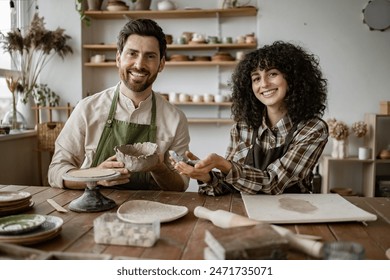 Smiling bearded man and woman sculpting clay vases and bowls in cozy art studio. Creative pottery workshop experience. - Powered by Shutterstock