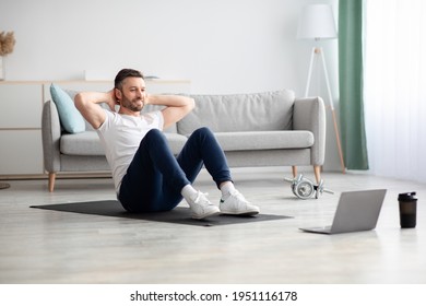 Smiling Bearded Man Working On Abs, Using Laptop And Fitness Mat At Home, Copy Space. Handsome Middle-aged Man In Sportswear Exercising In Living Room, Attending Online Fitness Class