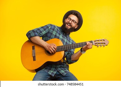 Smiling bearded musician man having fun and playing acoustic guitar. 
