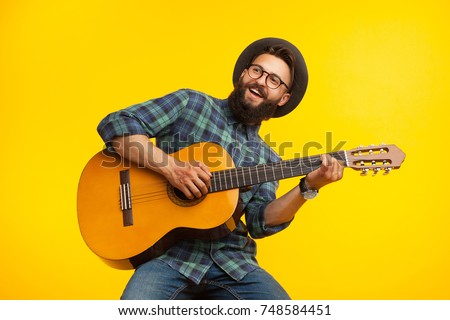 Smiling bearded musician man having fun and playing acoustic guitar. 