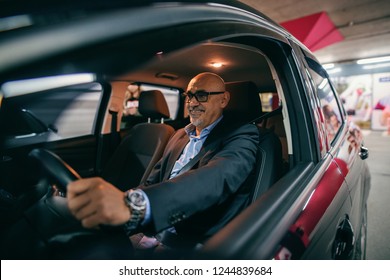 Smiling Bearded Senior Adult Driving Car At Night.