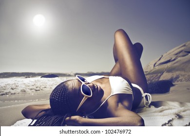 Smiling beautiful african woman lying on a beach in the sun