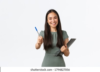 Smiling beautiful asian female shop assistant, employee asking to sign blank or shipping form, giving you pen as holding clipboard with documents, standing white background