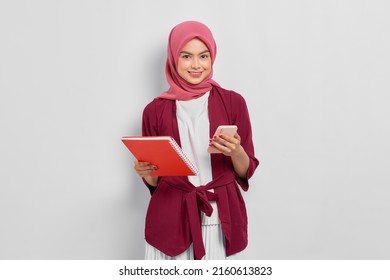 Smiling beautiful Asian woman in casual shirt holding mobile phone and notebook isolated over white background - Powered by Shutterstock