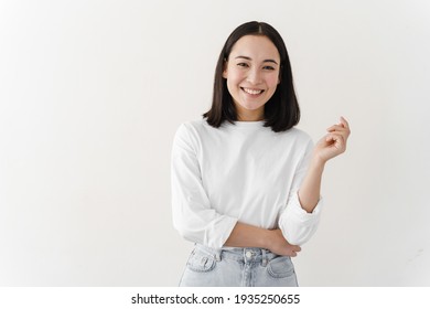 Smiling, beautiful brunette posing on a white wall. Young woman is standing at blank wall. - Powered by Shutterstock