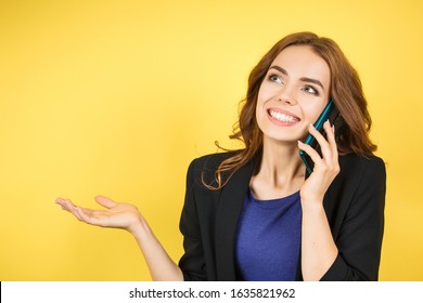 smiling beautiful business woman talking on a cell phone on yellow background - Shutterstock ID 1635821962
