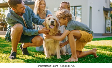 Smiling Beautiful Family of Four Posing with Happy Golden Retriever Dog on the Backyard Lawn. Idyllic Family Cuddling Loyal Pedigree Dog Outdoors in Summer House Backyard.