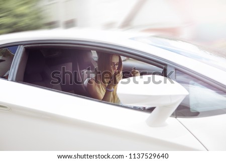 smiling, beautiful girl blond in glasses with an expensive white car on the road is standing