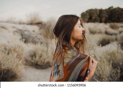 Smiling, beautiful hipster traveler girl in gypsy look and windy hair, in desert nature.  Artistic photo of young hipster traveler girl in gypsy look, in Coachella Valley in a desert valley in Souther - Shutterstock ID 1156093906