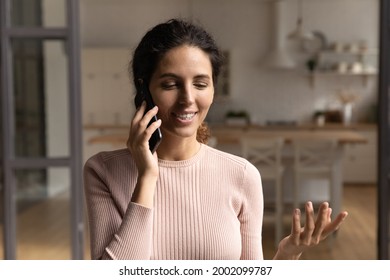 Smiling Beautiful Hispanic Latin Caucasian Woman Involved In Pleasant Cellphone Conversation, Calling Friends Or Talking With Family, Discussing Life News, Enjoying Distant Communication Alone At Home