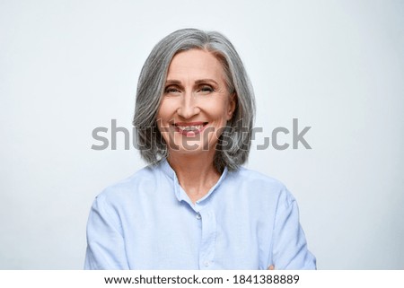 Smiling beautiful mature business woman standing isolated on white background. Older senior businesswoman, 60s grey haired lady professional coach looking at camera, close up face headshot portrait.