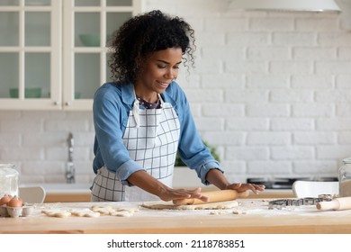 Smiling Beautiful Millennial Generation African American Woman Wearing Apron, Preparing Yeast Dough For Biscuit Cookies, Enjoying Baking Homemade Pastry Alone In Modern Kitchen, Hobby Activity.