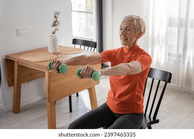 Smiling beautiful senior woman health instructor doing chair exercises with dumbbells - Powered by Shutterstock