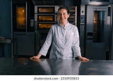 smiling beautiful woman baker in uniform stands near the oven before the start work bakery production of pastries - Powered by Shutterstock