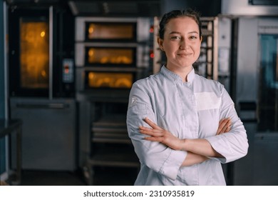 smiling beautiful woman baker in uniform stands near the oven before the start work bakery production of pastries - Powered by Shutterstock