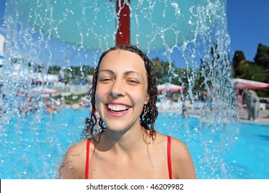 Smiling beautiful woman bathes in pool under water splashes, under fountain in form of mushroom