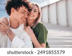 Smiling beautiful woman and her handsome boyfriend. Couple in casual summer clothes. Happy cheerful family. Female and man having fun. They posing in the street in sunny day. Sit at stairs