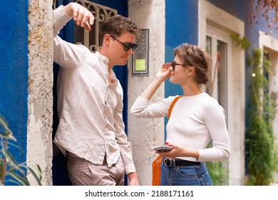 Smiling beautiful woman and her handsome boyfriend. Woman in casual summer jeans. Man standing near door woman flirting with handsome guy holding phone in hand - Shutterstock ID 2188171161