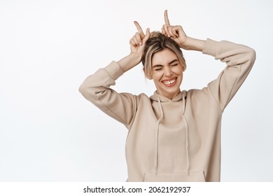 Smiling Beautiful Woman Laughing, Showing Bull Horns Fingers On Head, Standing Happy Against White Background